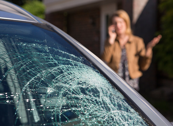 Woman Phoning For Help After Car Windshield Has Broken